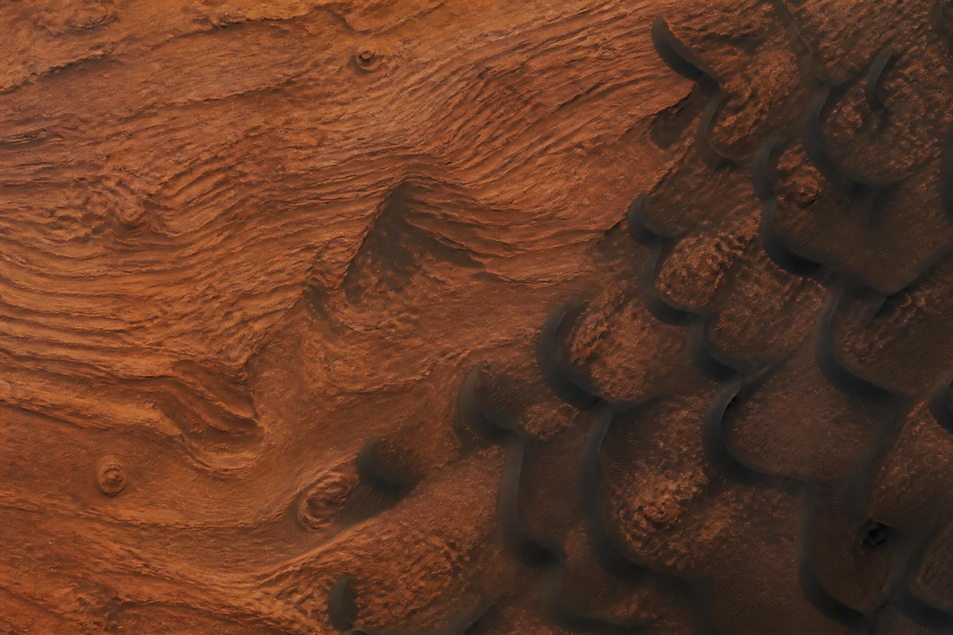 Layered Martian terrain and dark barchan dunes from orbit